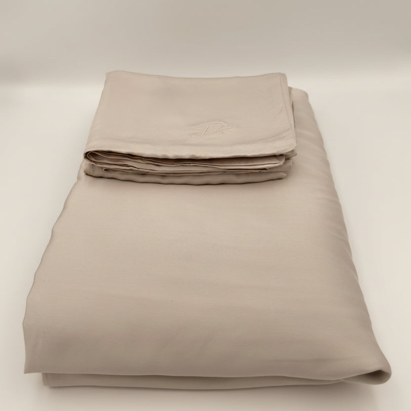 Folded beige bed sheet set on a white background