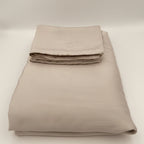 Folded beige bed sheet set on a white background