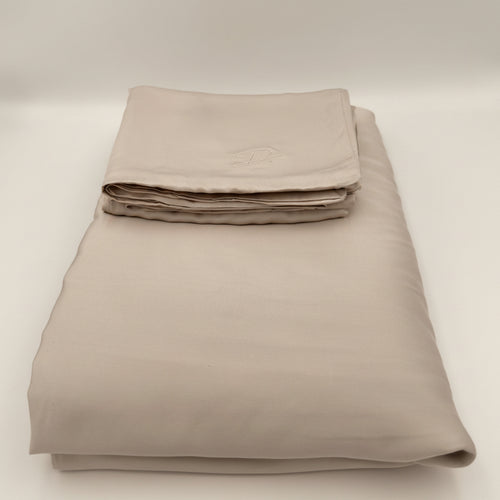 Folded beige bed sheet set on a white background