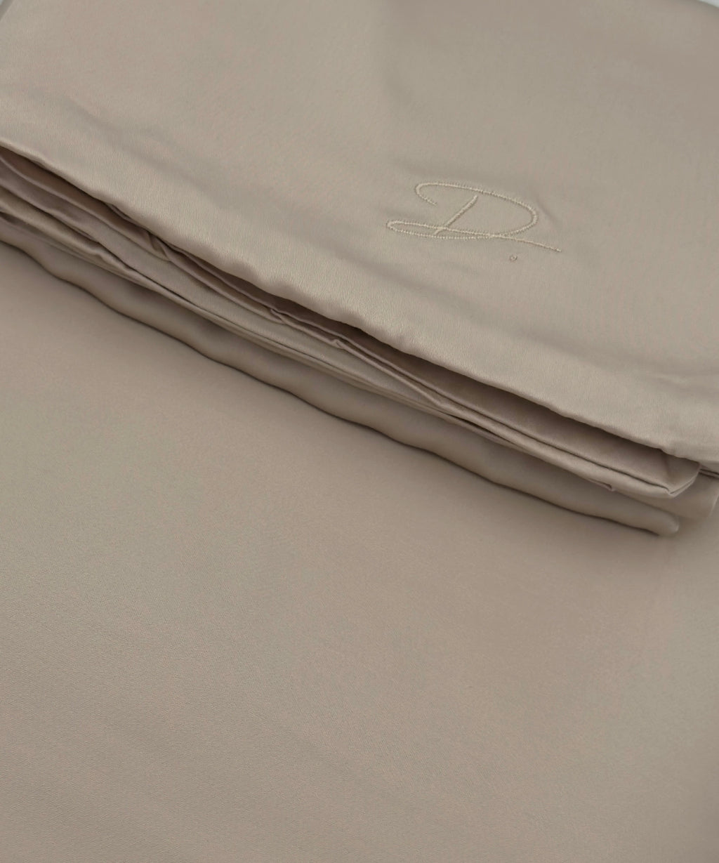 Folded beige fabric with a monogram on a plain background