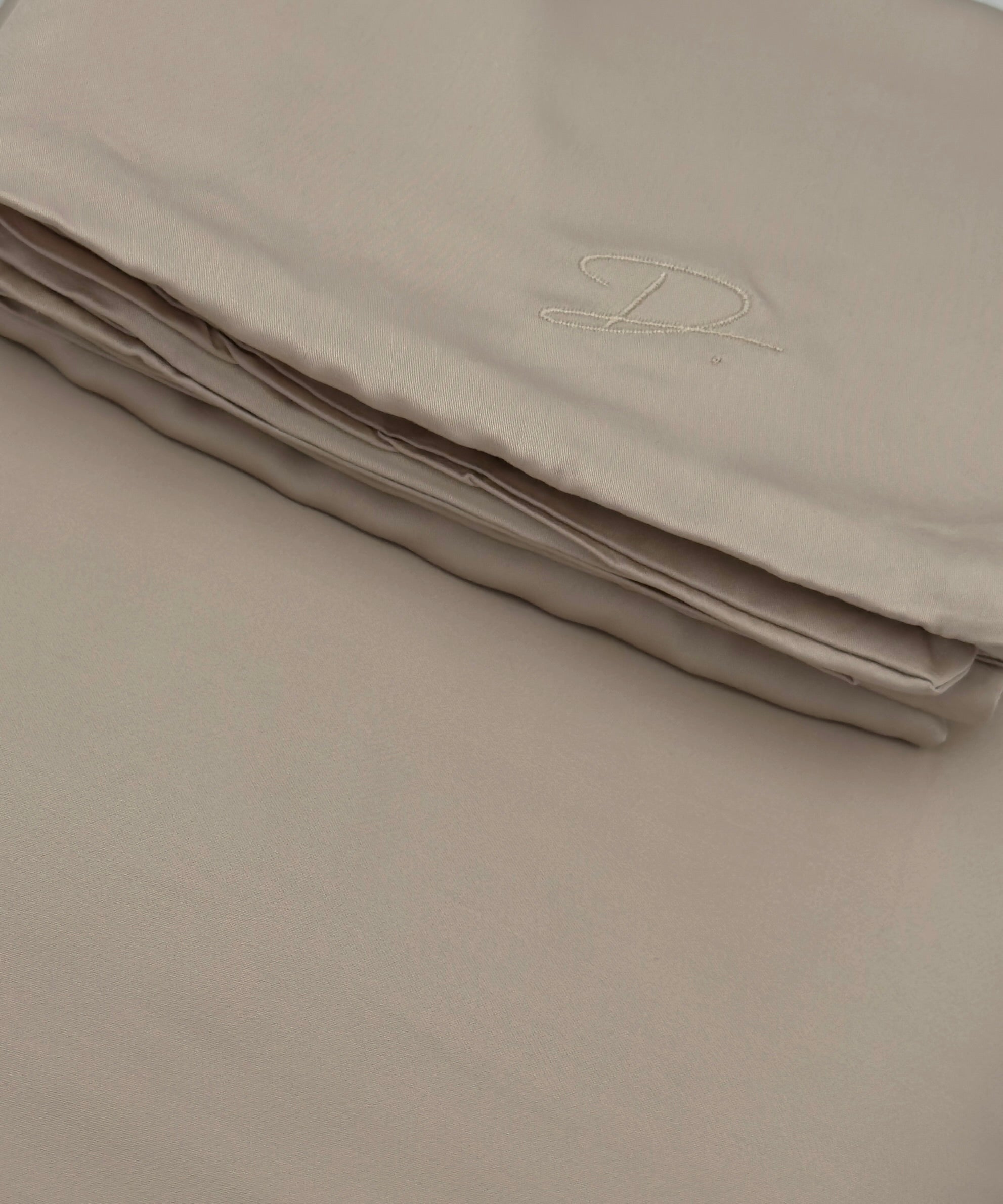 Folded beige fabric with a monogram on a plain background